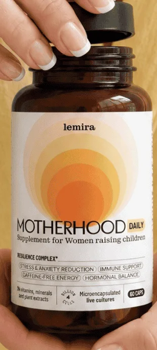 Lemira Motherhood Daily, brun glasburk med vit etikett som hålls i två händer